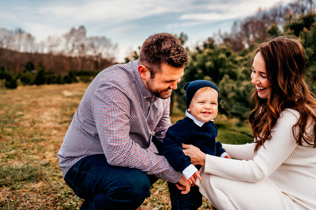 little boy smiling at camera with family during a tree farm session 